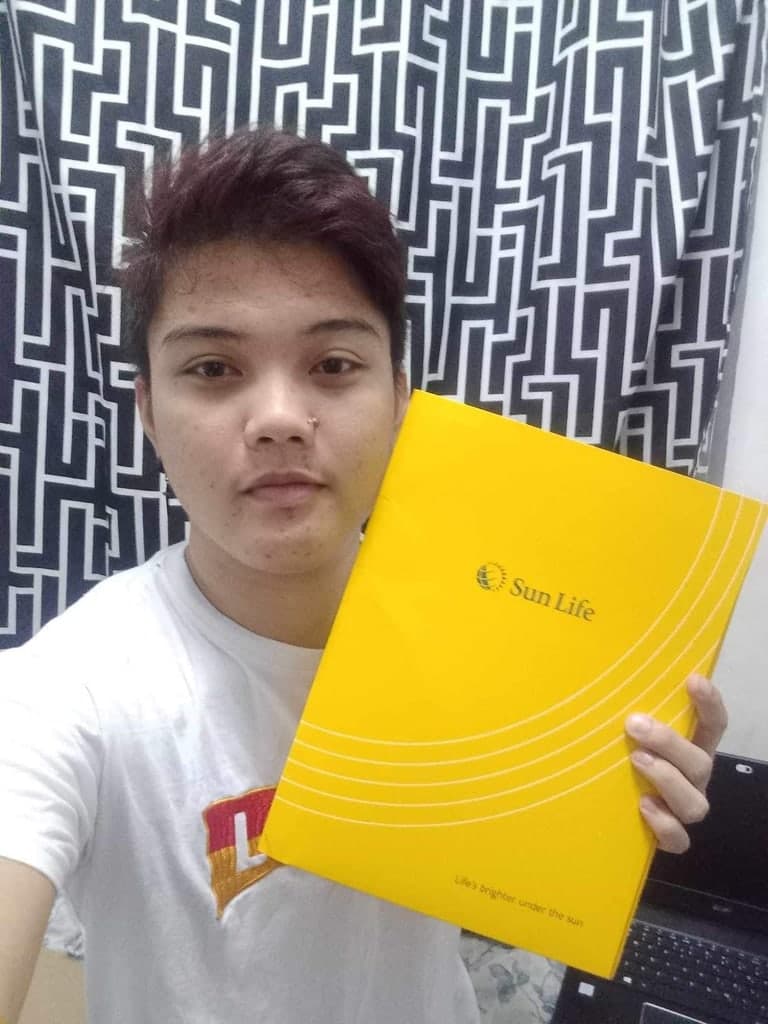 A client at home holding up her Sun Life policy folder to the camera