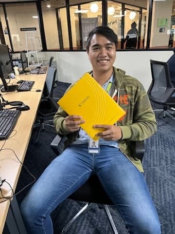 A young client at his office desk, holding the Sun Life folder containing his new policy