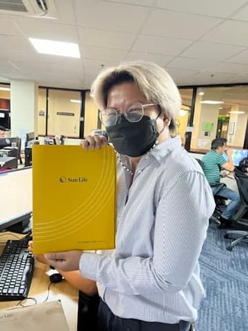 A client at her workstation holding the Sun Life folder with her new policy inside